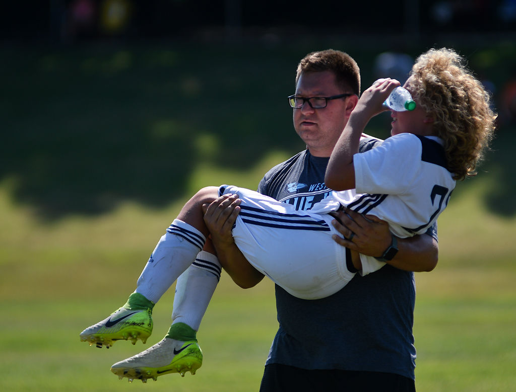 Brandon Russell carries player Clete Gott, 13, off the pitch